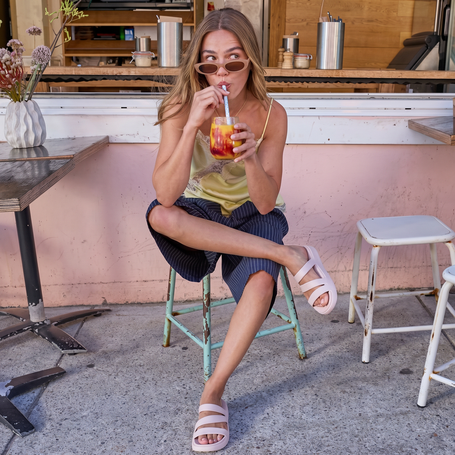 Woman at a bar wearing white MARISOLE strappy sandals